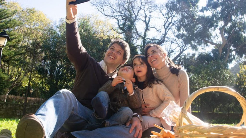 Happy family taking a selfie during a sunny picnic in a park.